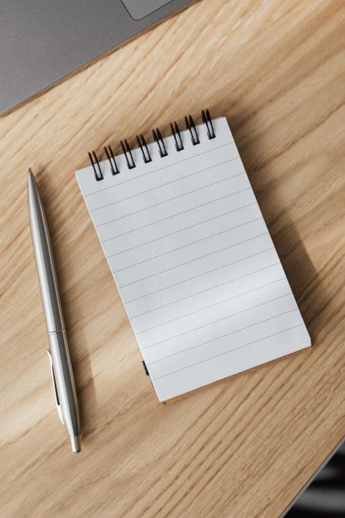 Minimalist stationery flat-lay with spiral notebook and pen on a natural wooden surface