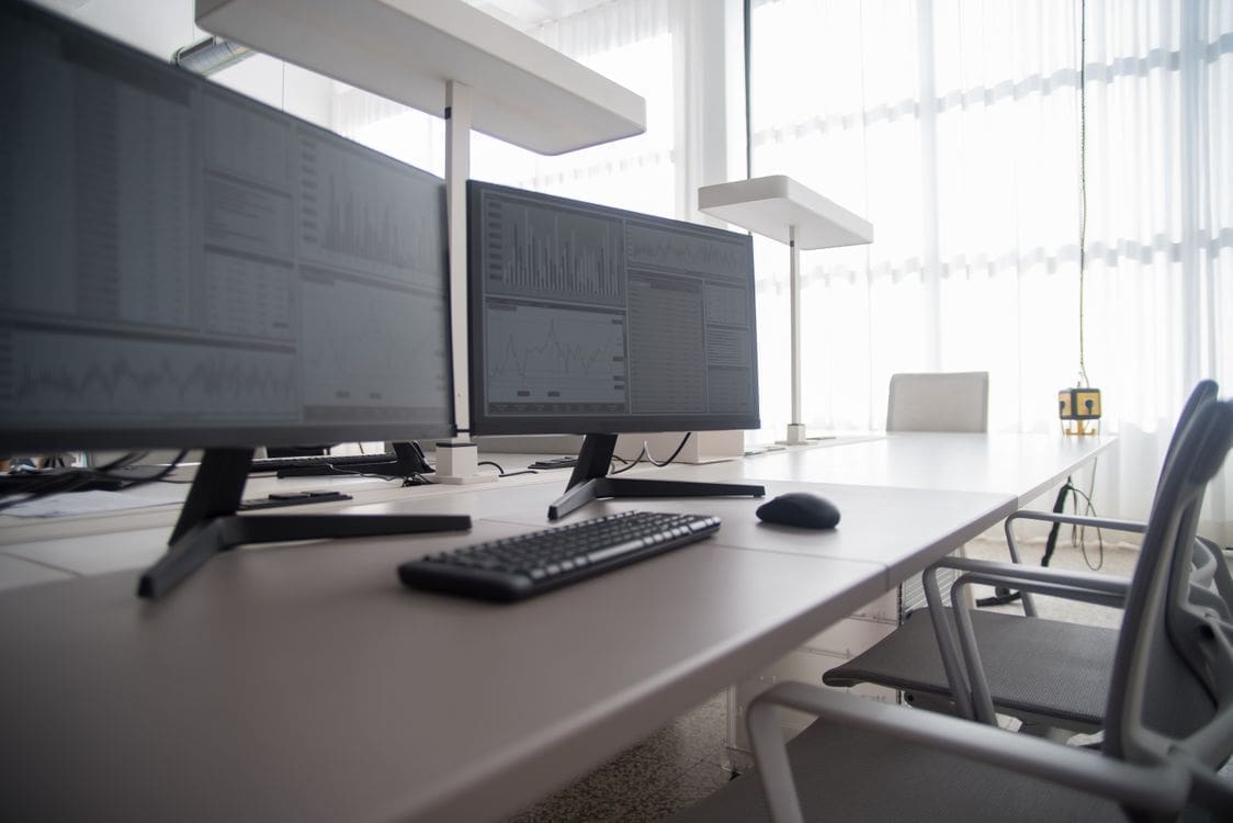 A modern home office featuring an ergonomic mesh chair with a desktop computer setup and warm lighting.
