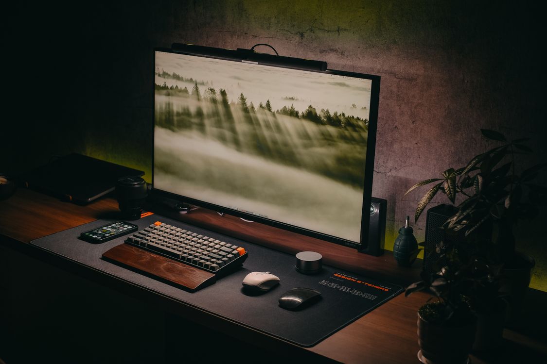 Computer setup on a wooden desk with keyboard and monitor in a cozy home office