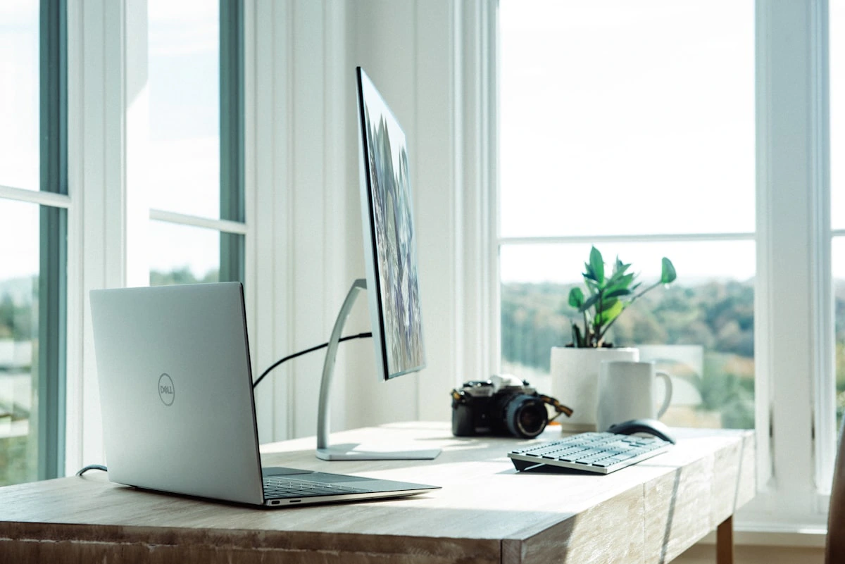A clean modern home office workspace with monitor, keyboard and ergonomic chair arrangement