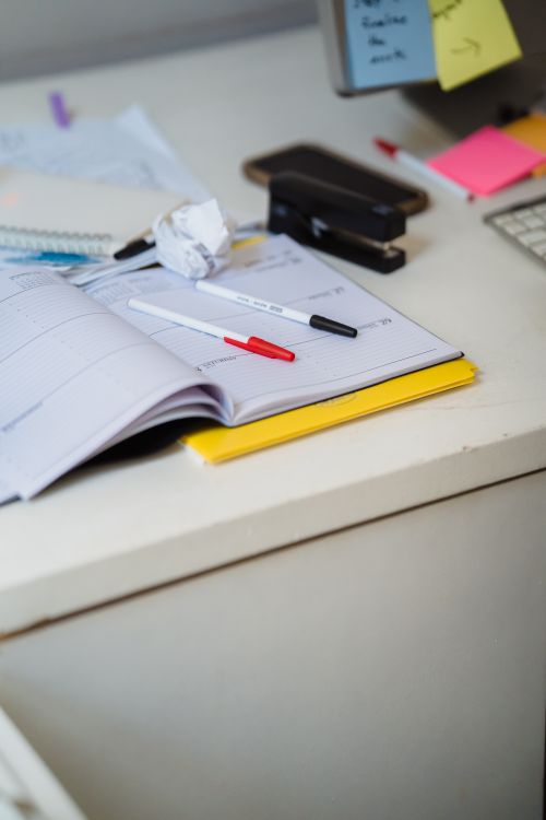 Colourful pens and a planner arranged on an organized office desk