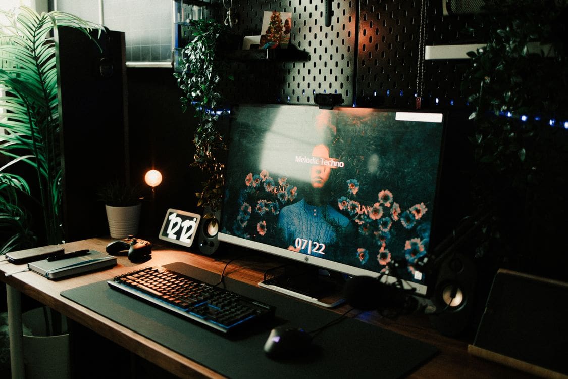 Stylish home office desk featuring a computer setup with keyboard, notebook and plants