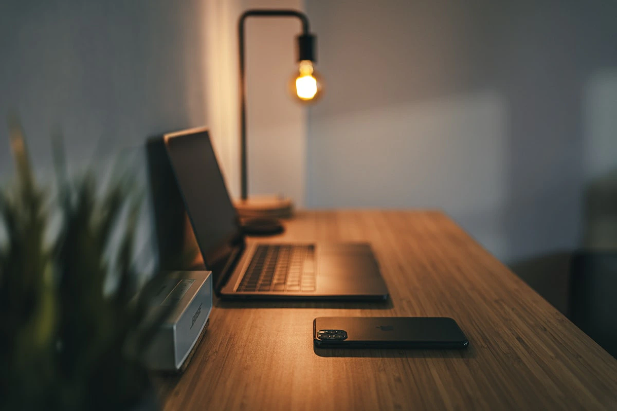 A home office desk with a laptop on a wooden stand and ergonomic accessories in natural light