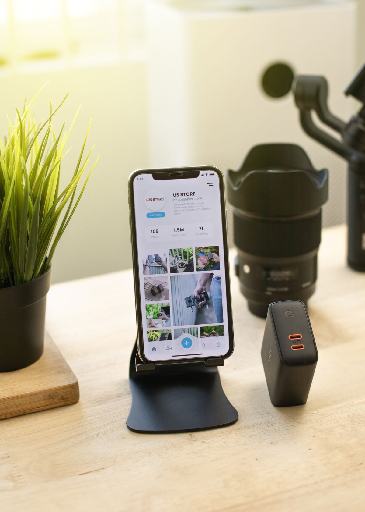 Modern smartphone on an adjustable desk holder beside gadgets and a plant in a clean workspace