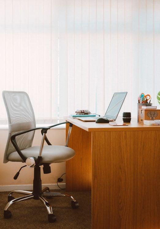 Clean home office setup with an ergonomic chair and wooden desk in soft natural light