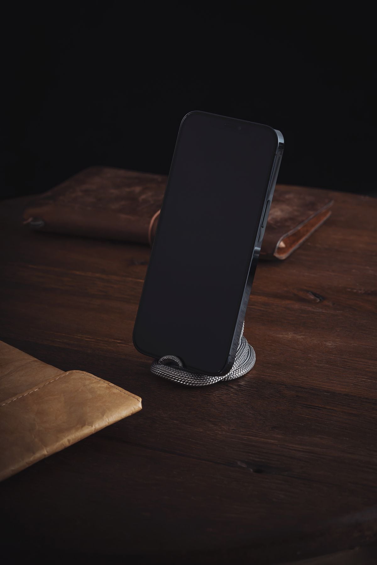 Smartphone displayed on a silver stand on a wooden table