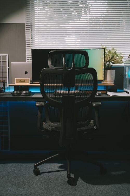 Modern home office desk with a widescreen monitor and ergonomic chair