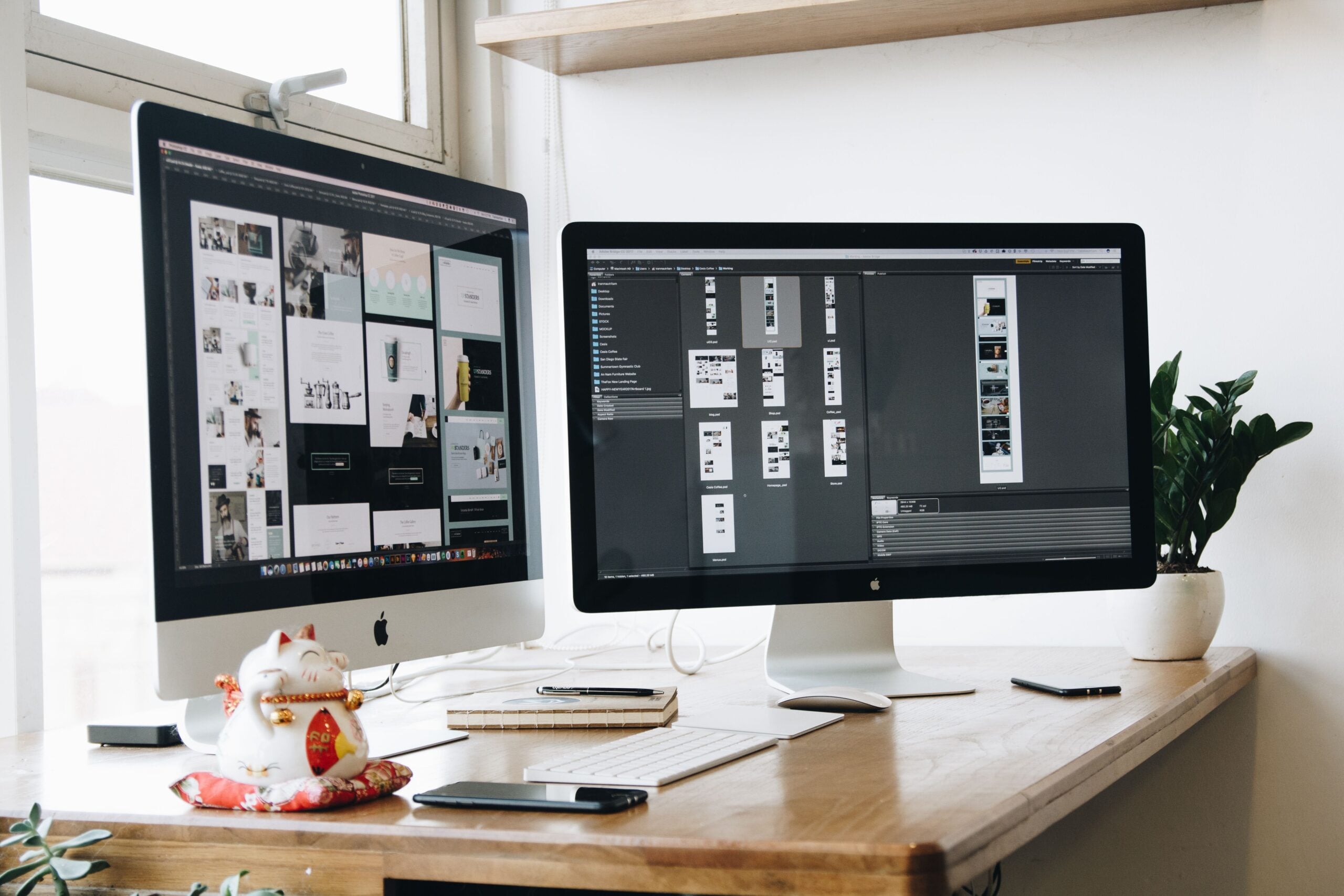 A clean wooden desk with dual monitors, keyboard and a small plant in a bright workspace