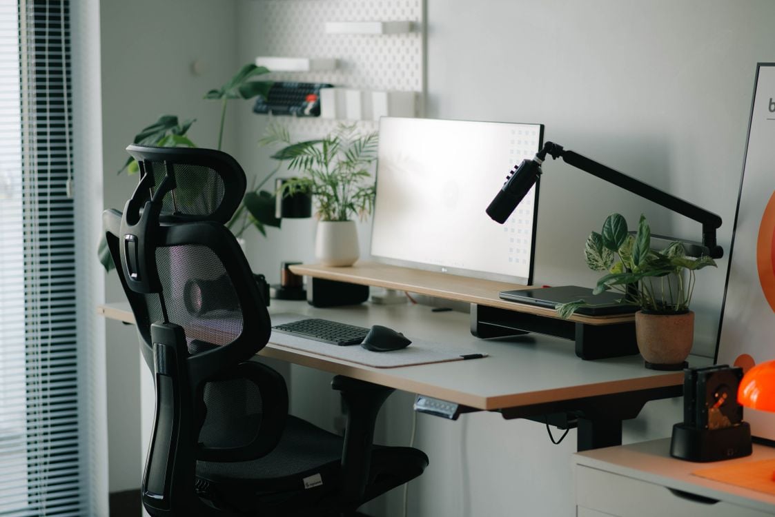 Modern home office desk with an ergonomic chair and plants in a bright workspace
