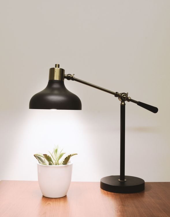 Black metal desk lamp lighting a workspace with warm, focused task light