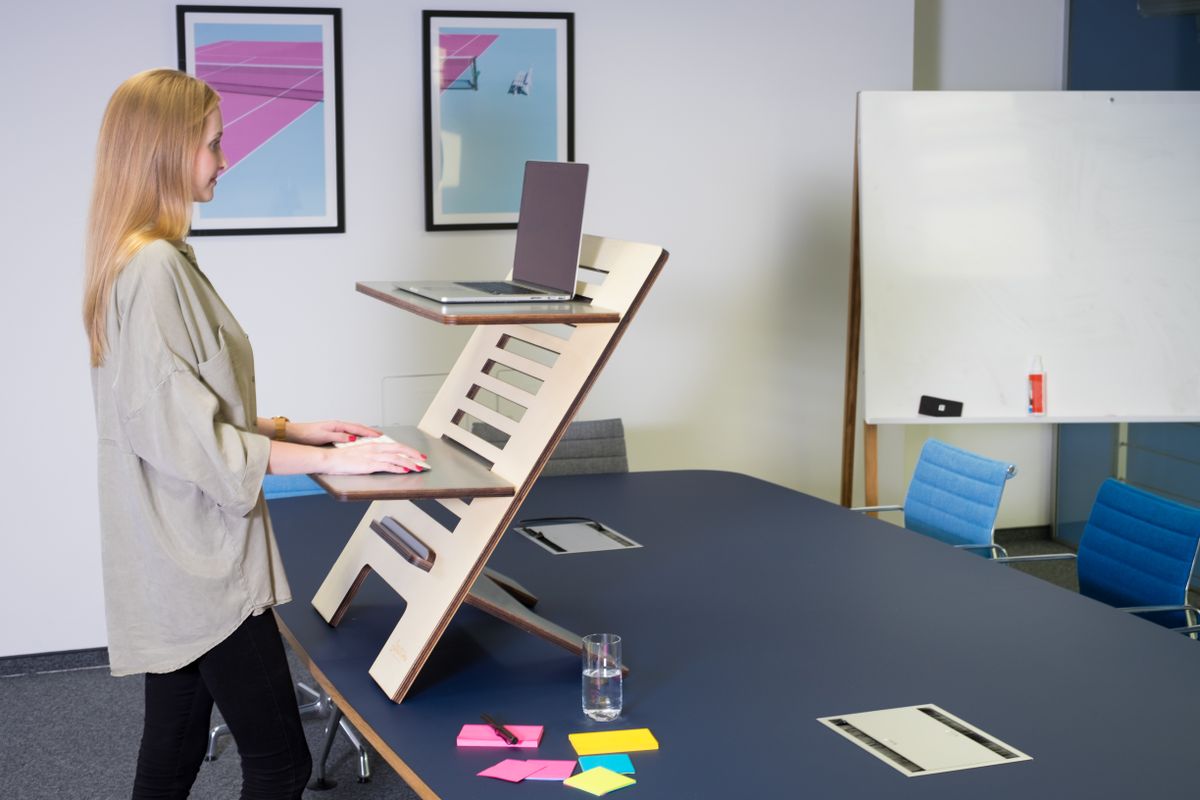 Woman standing at a height-adjustable desk working on a laptop in a modern home office